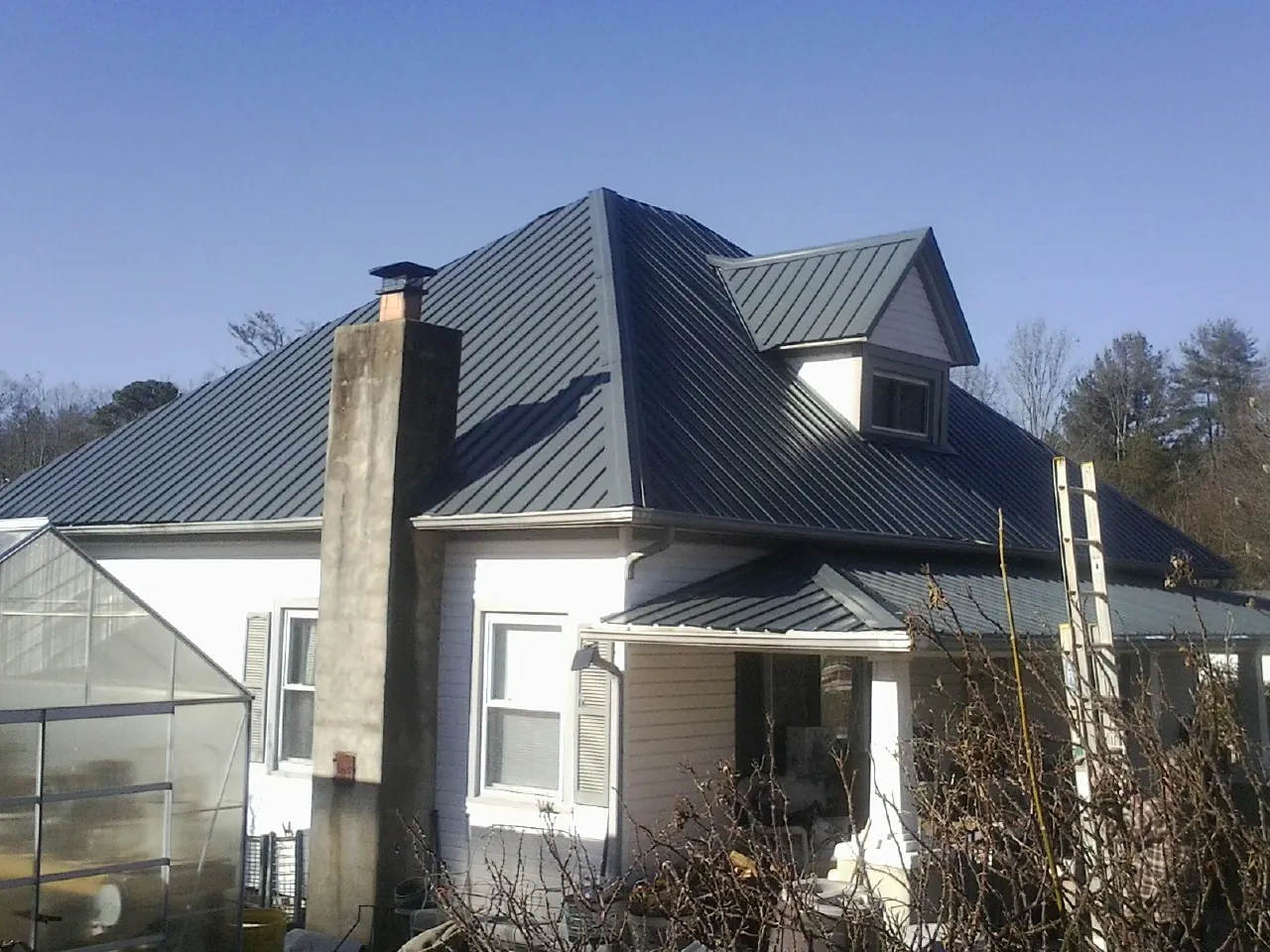 Dark blue standing seam metal roof on a white farmhouse with dormer — Slate & Tile Roof Repair by Roofing Brothers in Pomfret Center