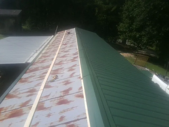 Old rusted panels beside newly installed green metal roofing — Wind Damage Roof Repair by Roofing Brothers in Pomfret Center