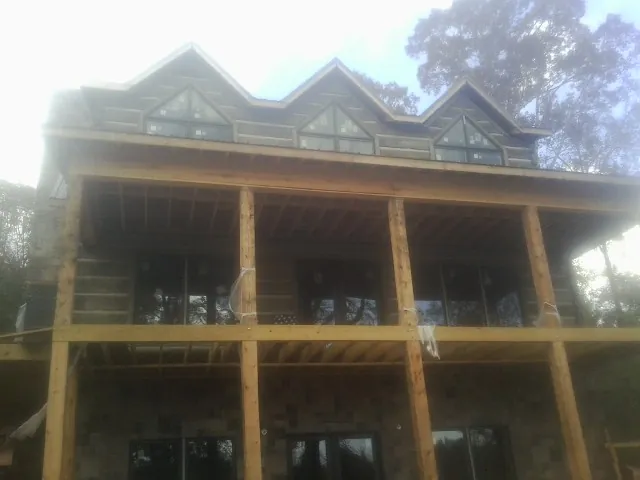 Dormers and porch framing on a large log home under construction — Roof Coating work by our crew in Pomfret Center