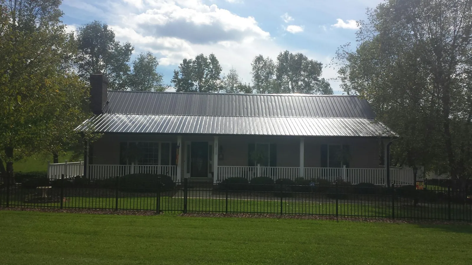 Gray metal roof on a brick ranch with a full width front porch — Gutter Guard Installation work by our crew in Pomfret Center