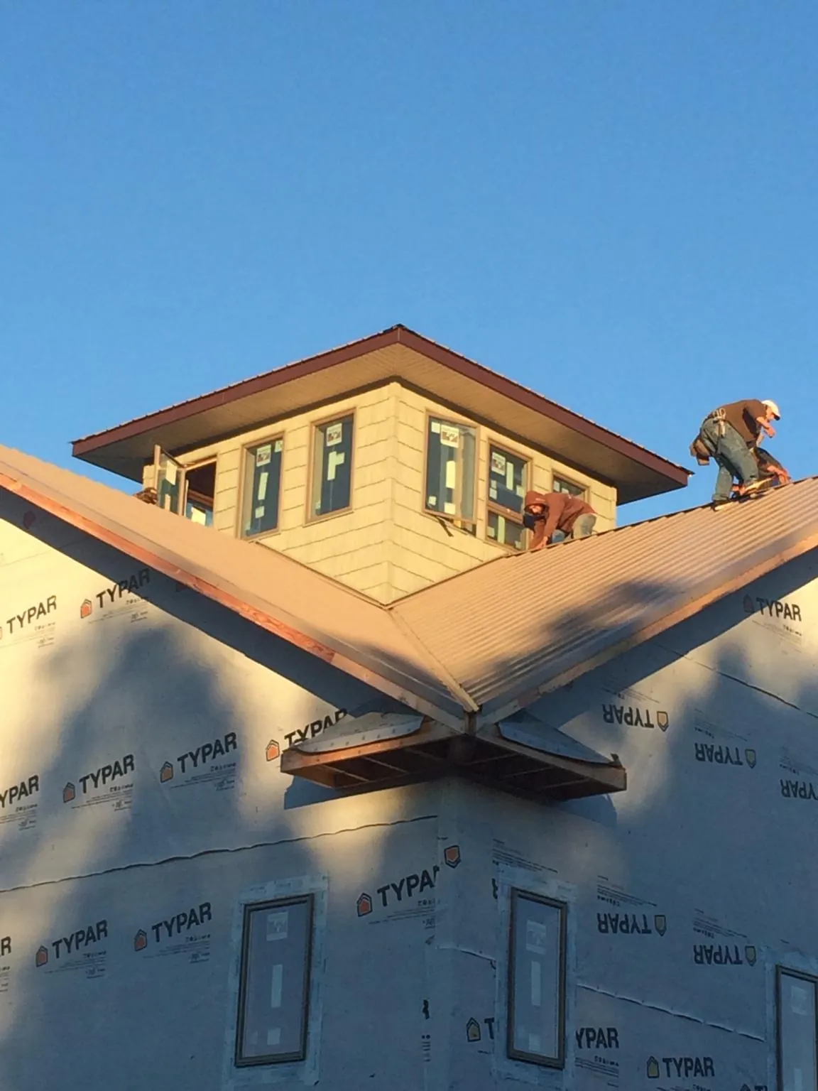 Roofers working around a rooftop cupola on a new metal roof at sunset — Roof Waterproofing in Pomfret Center by Roofing Brothers